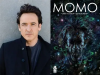 IL – Momo Signing | Nov 5th A portrait of John Cusack next to the cover of his graphic novel, “Momo,” illustrated by Ignacio Noé.